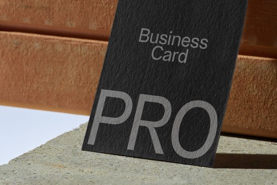 Elegant business card mockup with textured design and typography standing against a concrete and brick background for graphic designers.