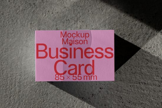 Pink business card mockup with shadow on concrete surface, showcasing design presentation for graphic designers.