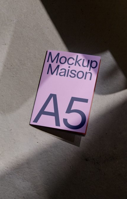 A5 size pink mockup book on concrete surface with shadows, design presentation, realistic mockup for portfolio display.