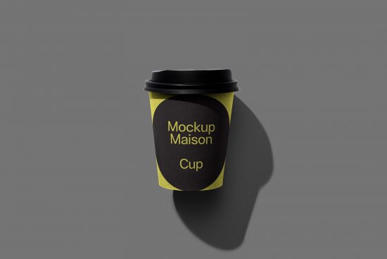 Coffee cup mockup with black lid, yellow label design on gray background, ideal for branding and packaging presentations.