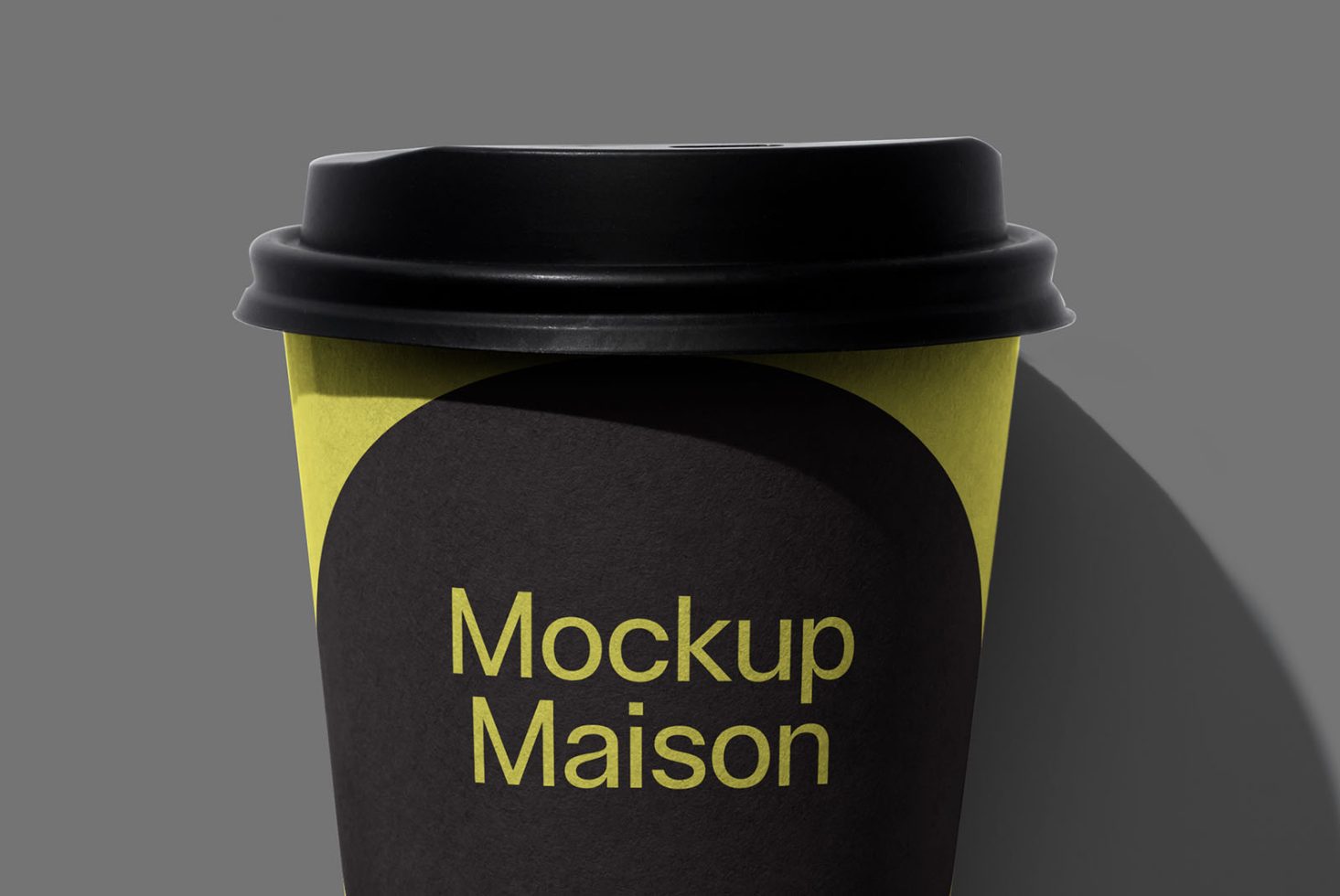 Close-up of a paper coffee cup mockup with black lid and stylish yellow accent design on a gray background, suitable for branding presentations.