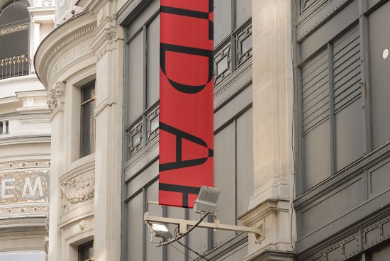 Red urban banner mockup hanging on a classic building, with clear space for designers to showcase branding graphics and logos.