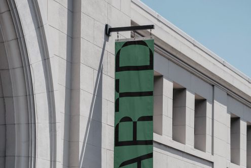 Wall-mounted signage mockup on building facade with clear sky, ideal for logo presentation and branding projects for designers.