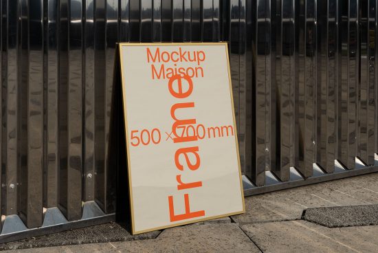 Outdoor sidewalk signboard mockup leaning against a fence, ideal for showcasing branding designs and fonts, sized at 500x700 mm.