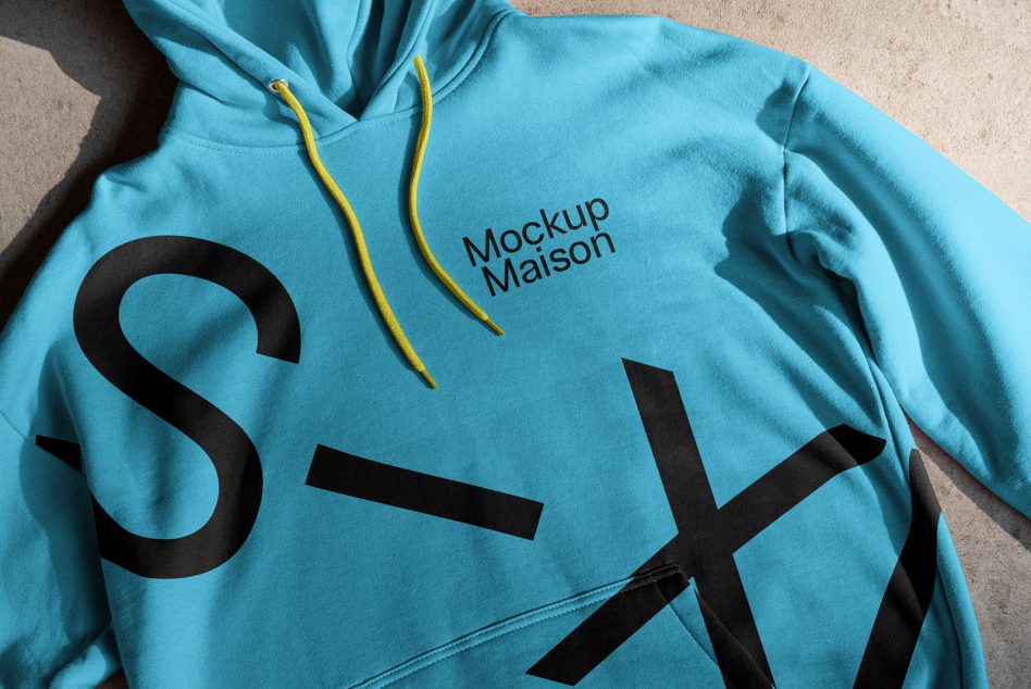 Blue hoodie mockup with graphic design and yellow drawstrings, shadow detail, realistic apparel presentation for fashion designers.