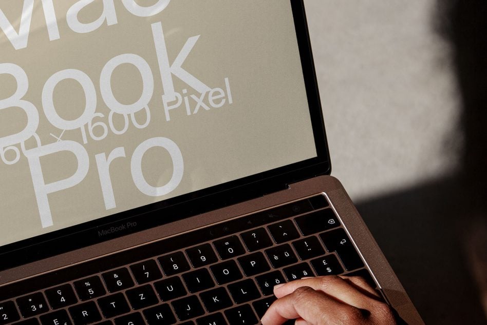 MacBook Pro with hands typing, beige screen showing white text mockup