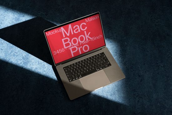 Laptop mockup with dramatic shadow on blue surface, featuring a MacBook Pro with red screen display ideal for presentations, digital designs.