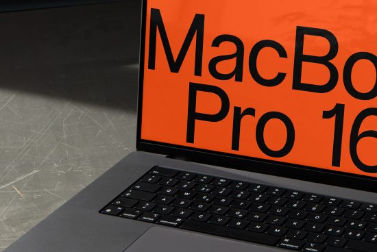Close-up of a modern laptop with vibrant orange screen mockup on a textured surface, ideal for designers' device template presentations.