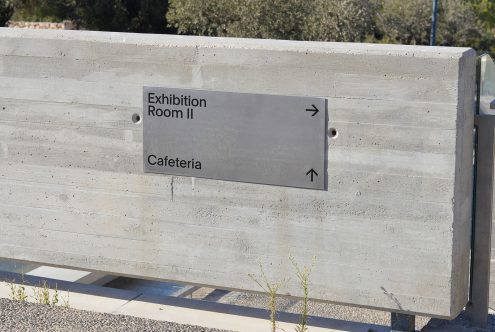 Minimalistic directional sign mockup attached to concrete wall with clear typeface, suitable for wayfinding design presentations.