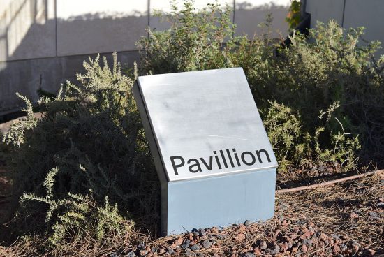 Sleek outdoor sign mockup nestled in natural setting with modern font showcasing "Pavillion" text ideal for graphic designers and signage templates.