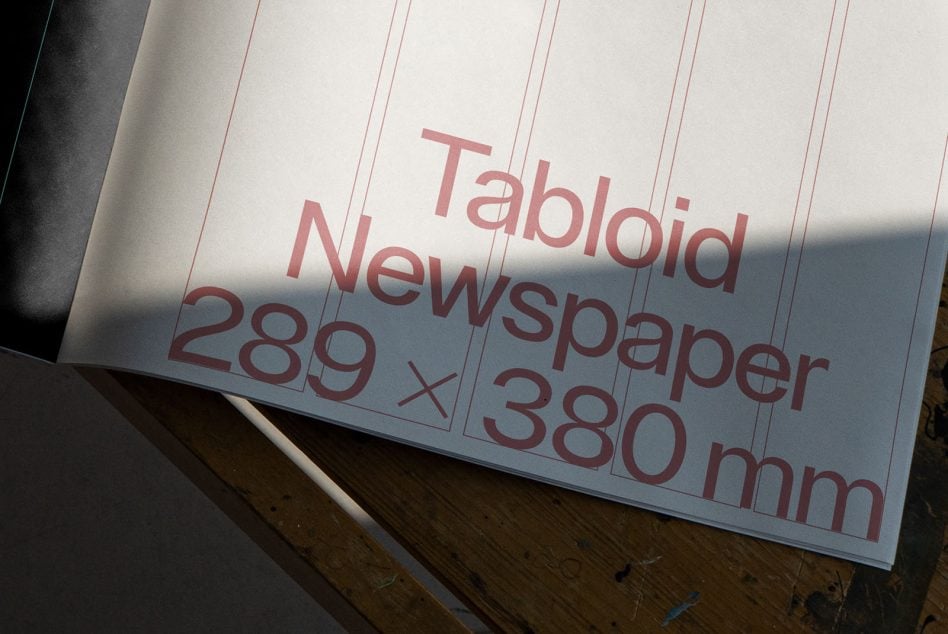 Open white newspaper spread showing tabloid layout with pink typography