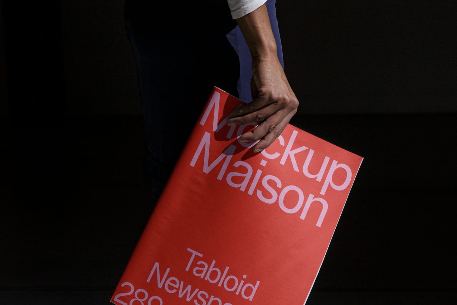 Person holding a red tabloid-sized mockup with bold typography design ideal for presenting editorial and graphic designs on a marketplace.