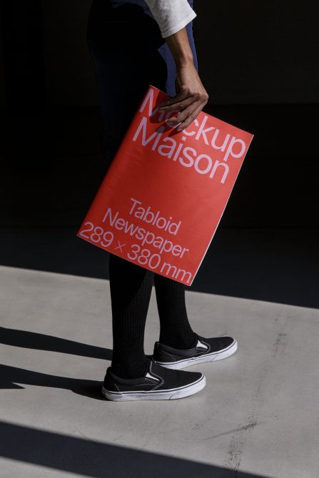 Person holding a red poster mockup with bold typography for print design presentation, graphic design, and marketing.