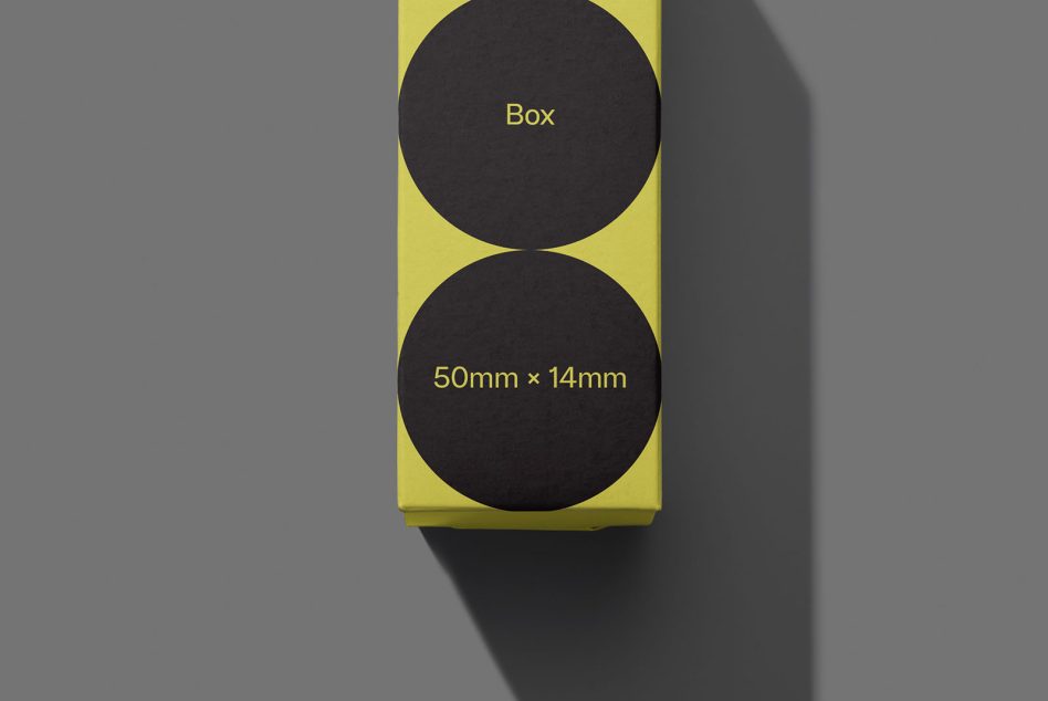 Yellow packaging box mockup with black circles, shadow casting on grey, dimensions labeled, ideal for presentations, graphic design.