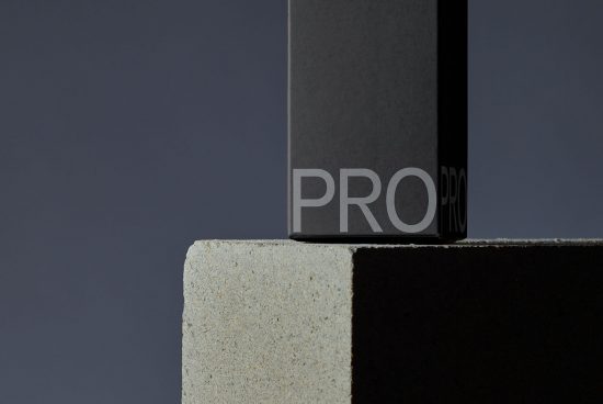 Minimalist black packaging mockup on concrete block with subtle textures, ideal for sleek product design presentation.