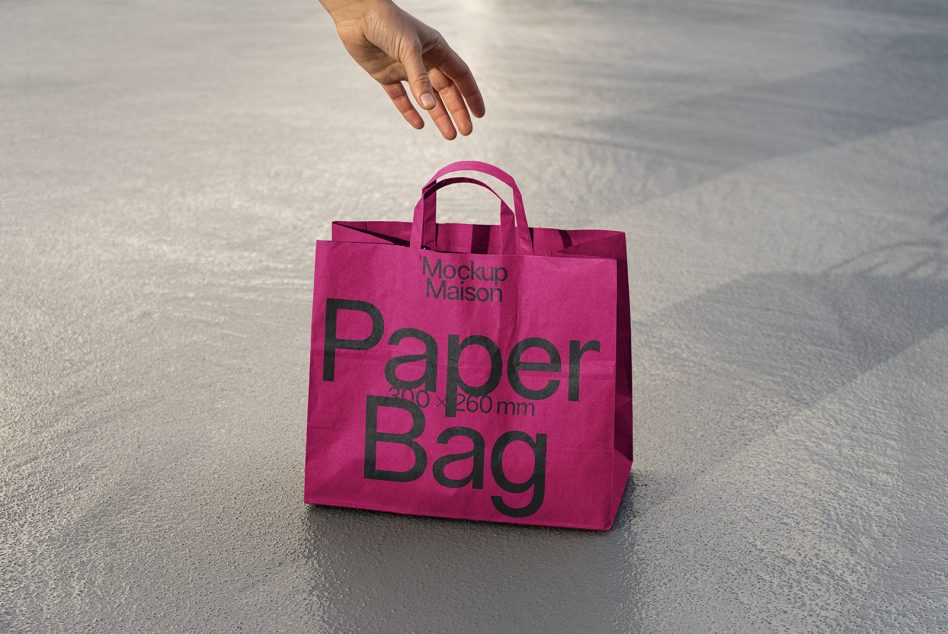 Pink paper bag mockup on concrete surface with hand reaching out, real shadow, product packaging design template.