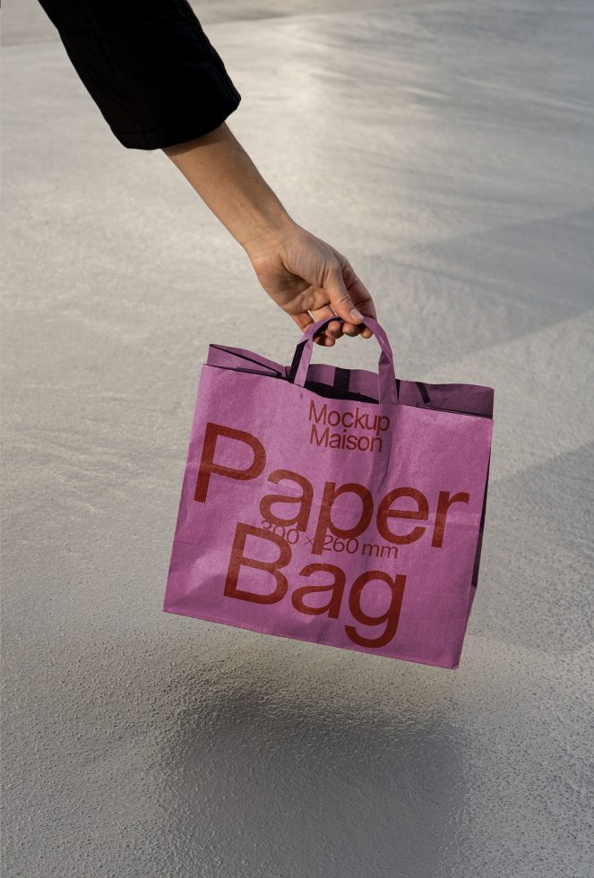 Person holding a purple paper bag mockup with text, ideal for branding presentations and packaging design on a textured background.