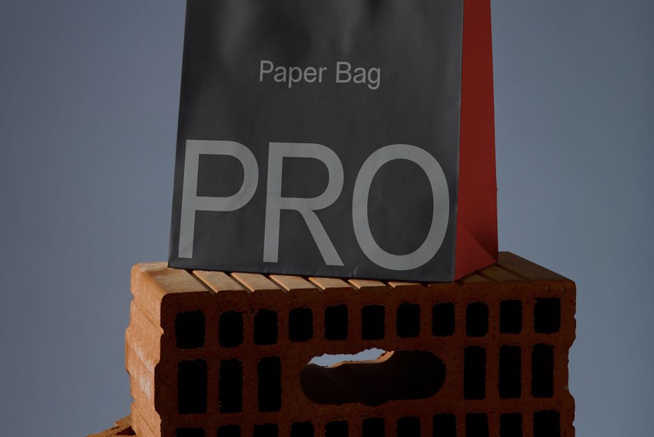 Elegant black paper bag mockup on brick showing PRO text, ideal for product branding presentations and packaging designs.