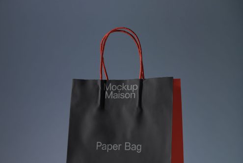 Black paper bag mockup with red handles on a blue background, ideal for branding presentation, graphic design showcase.