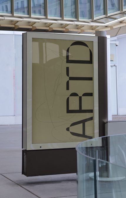 Indoor poster board with tan background showing stacked geometric forms with line details