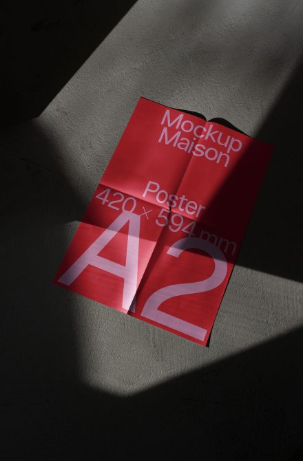 Red A2 poster mockup with shadow overlay on concrete surface, ideal for showcasing graphic design work and typography layouts.