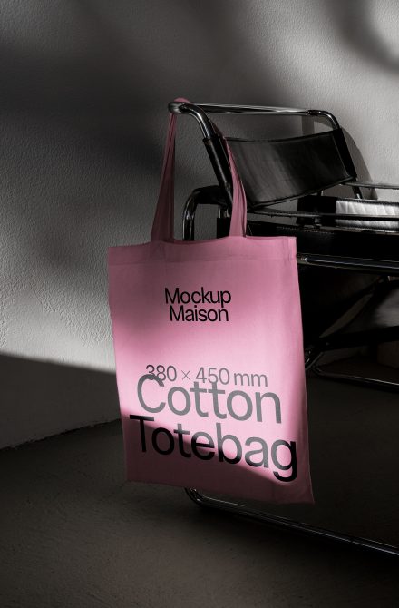 Stylish cotton tote bag mockup hanging on a modern chair to showcase design, with a muted pink color in a contemporary interior setting.