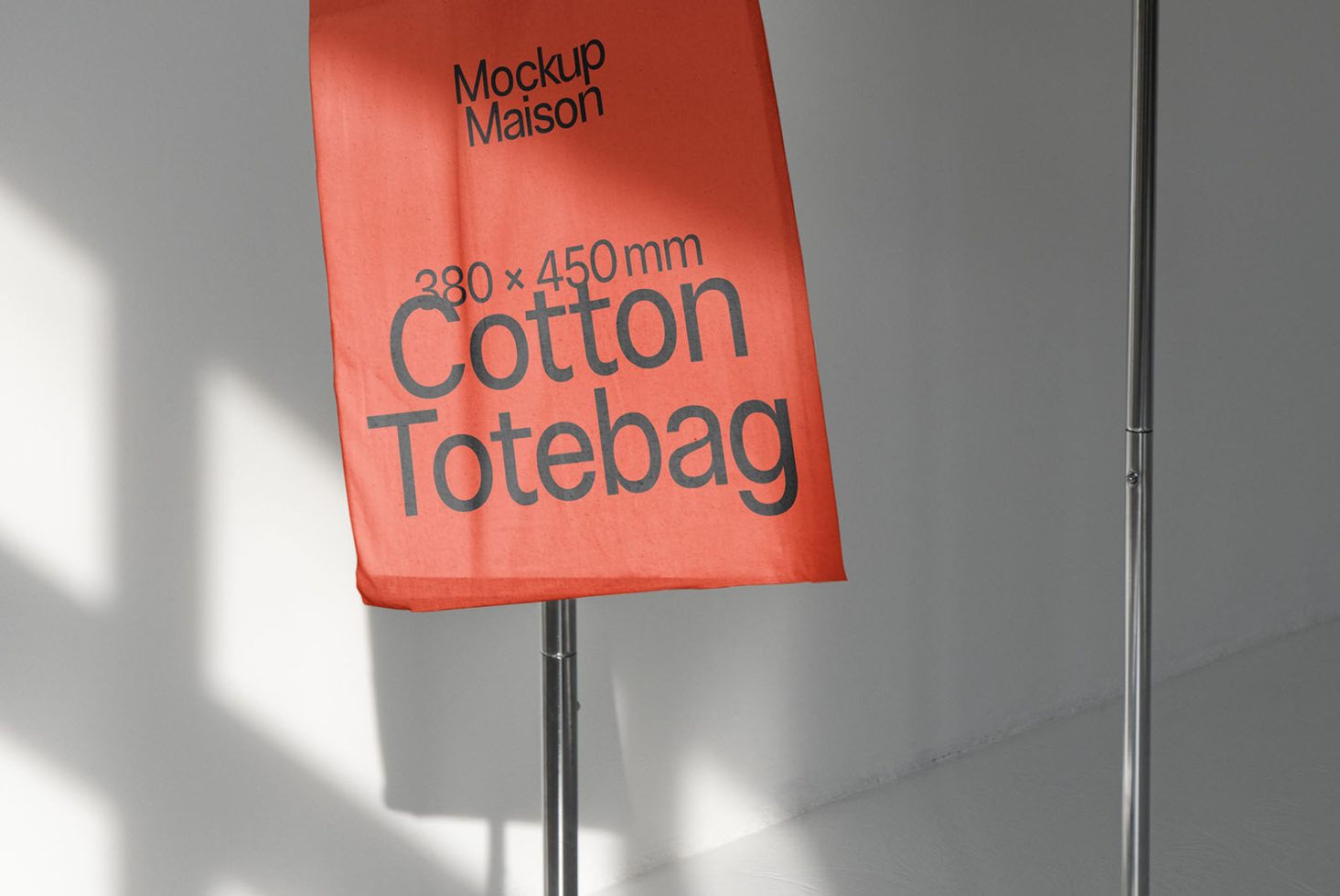 Orange cotton tote bag mockup on metal stand with shadow play, highlighting product design and dimensions for digital asset marketplace.