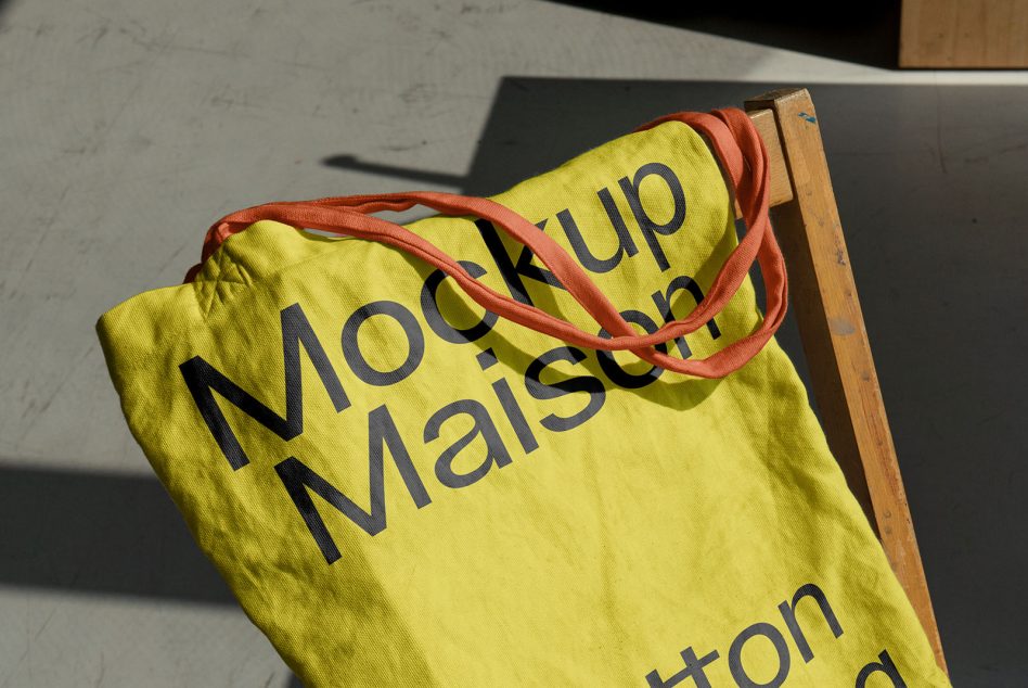 Yellow tote with coral handles draped over rustic wooden pallet in sunlight