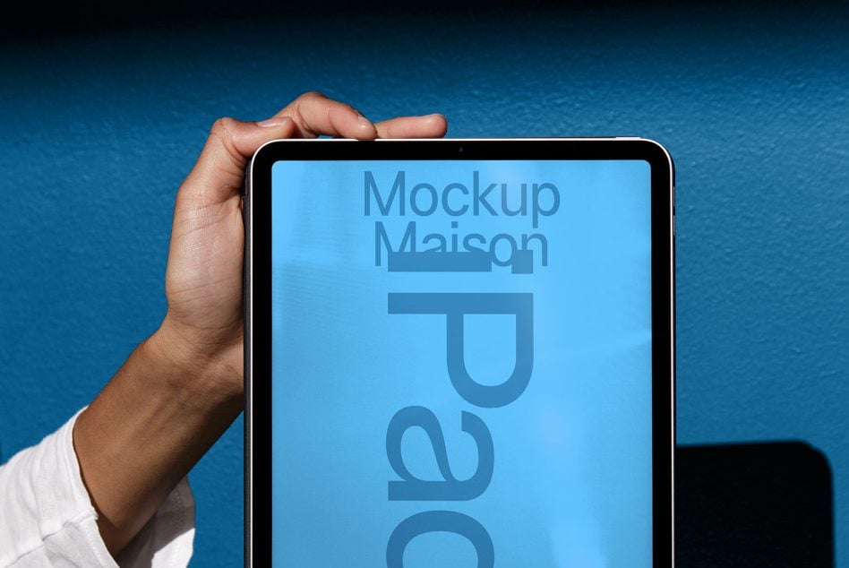 Hands holding tablet with blue screen on blue background side view