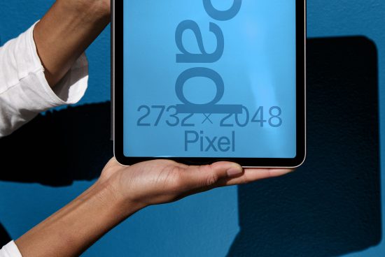 Person holding tablet screen mockup with resolution label against blue wall, ideal for presenting UI UX designs, digital product display.