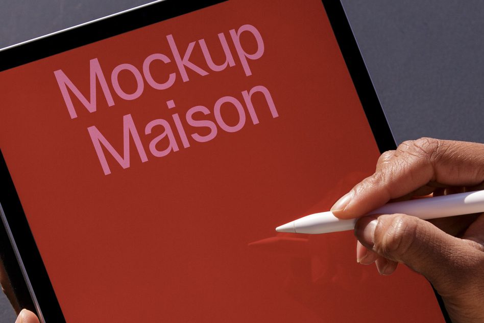 Tablet held in hands with stylus, red screen displaying text, overhead view