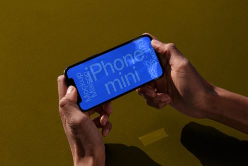 Hands holding smartphone with blue screen mockup on olive background, showcasing design space for apps, graphics, and mobile interfaces.