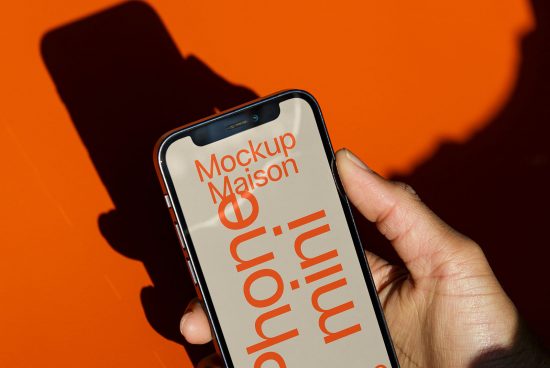 Hand holding smartphone displaying minimalist font design with orange background, ideal for mockup graphics and font design showcase.