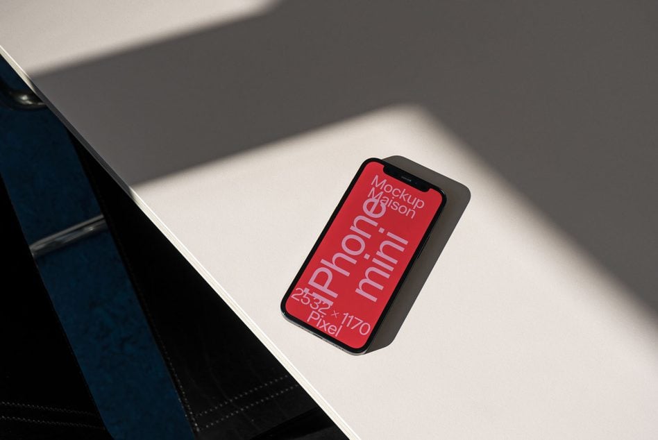 iPhone mockup on white desk with red screen showing mobile dimensions, styled product shot