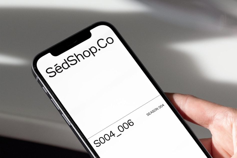 Smartphone in hand showing SédShop.Co interface with season 004 branding