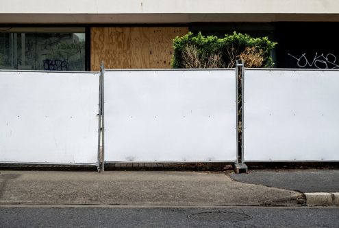 Urban street scene with a white barrier fence, tagging graffiti on a building, ideal for mockup background in cityscape settings.