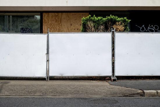 Urban street scene with a white barrier fence, tagging graffiti on a building, ideal for mockup background in cityscape settings.