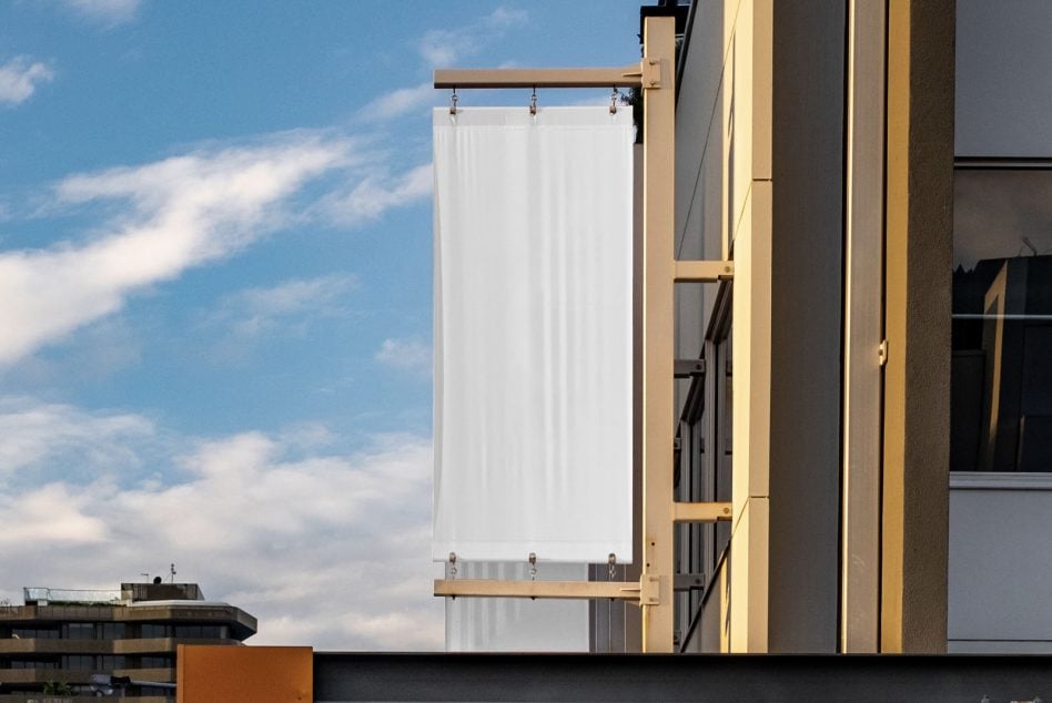 Blank vertical banner mockup hanging on building exterior against sky