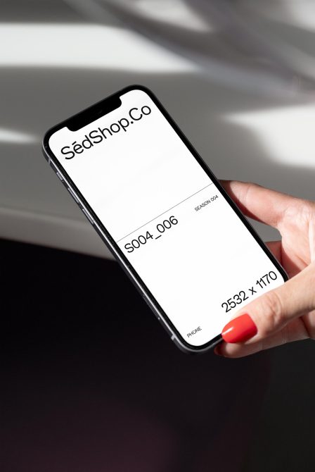Black smartphone held in hand showing mobile screen mockup with red nails