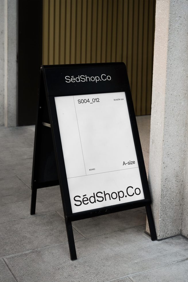 Black A-frame sidewalk signboard mockup standing outside, with editable display areas for templates, graphics, and branding designs.