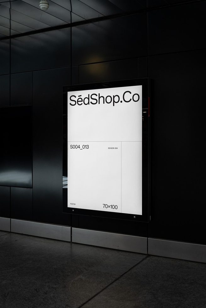 Vertical poster mockup on a black wall in a modern setting, presenting a clean design space for graphics display.