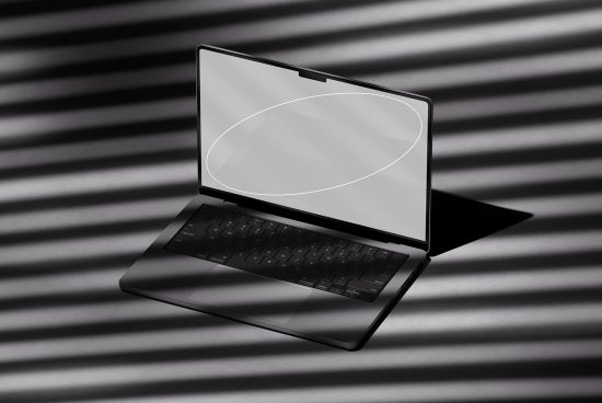 Modern laptop open on desk with striking shadow pattern, ideal for mockup designs, technology graphics, and digital asset presentations.