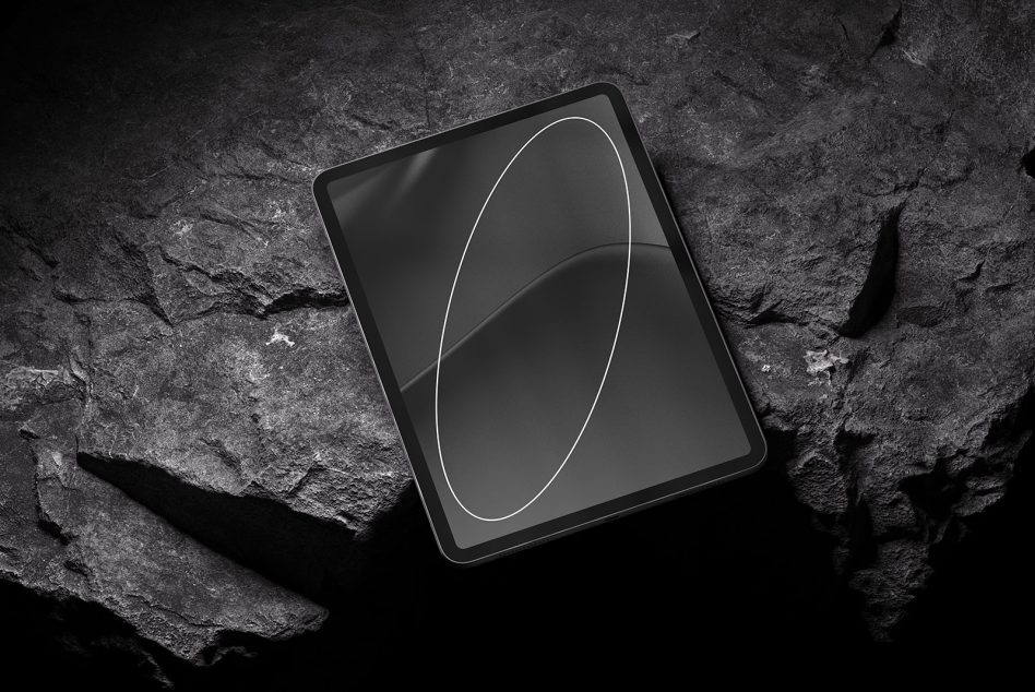 Tablet on rough stone backdrop with subtle line art on dark screen