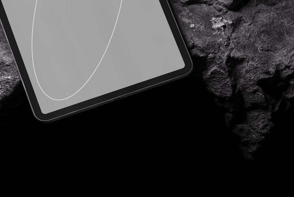 Tablet corner detail against dark textured rock surface, minimal aesthetic