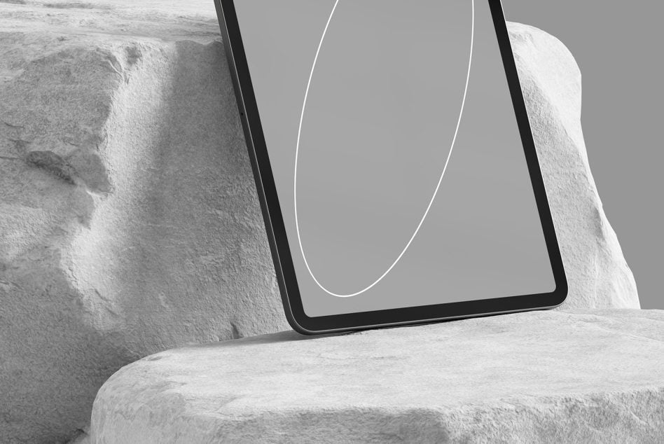 Tablet mockup leaning against white stone with blank gray display