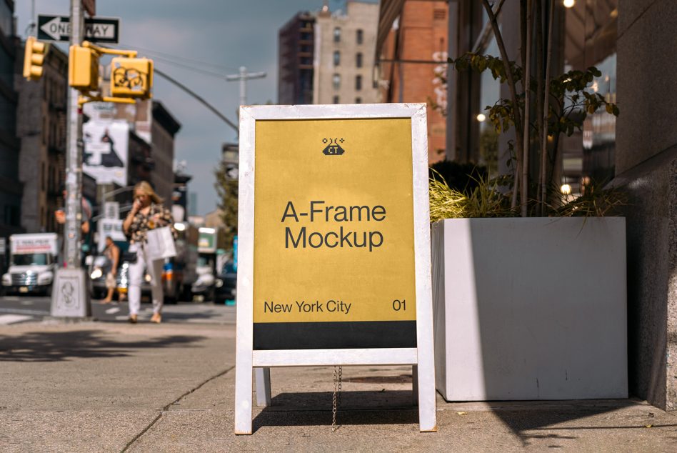 White-framed yellow A-frame sign on NYC sidewalk near traffic signals