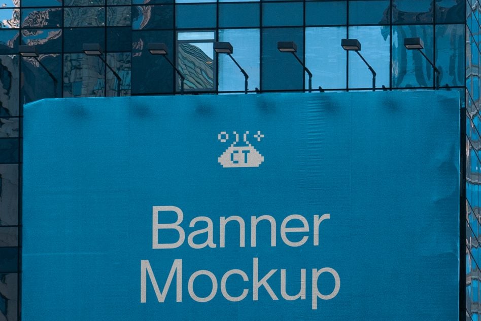 Teal billboard on glass building facade reflecting sky over cityscape
