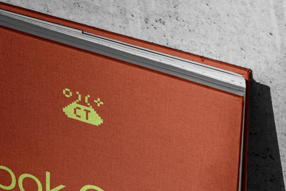 Closeup of red fabric book cover with lime green pixel logo on spine