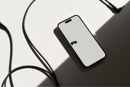 Smartphone mockup surrounded by black charging cables on white surface