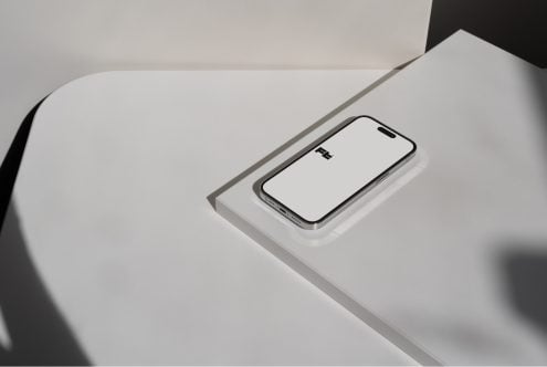 iPhone 14 Pro mockup on curved white surface, angled view, empty screen